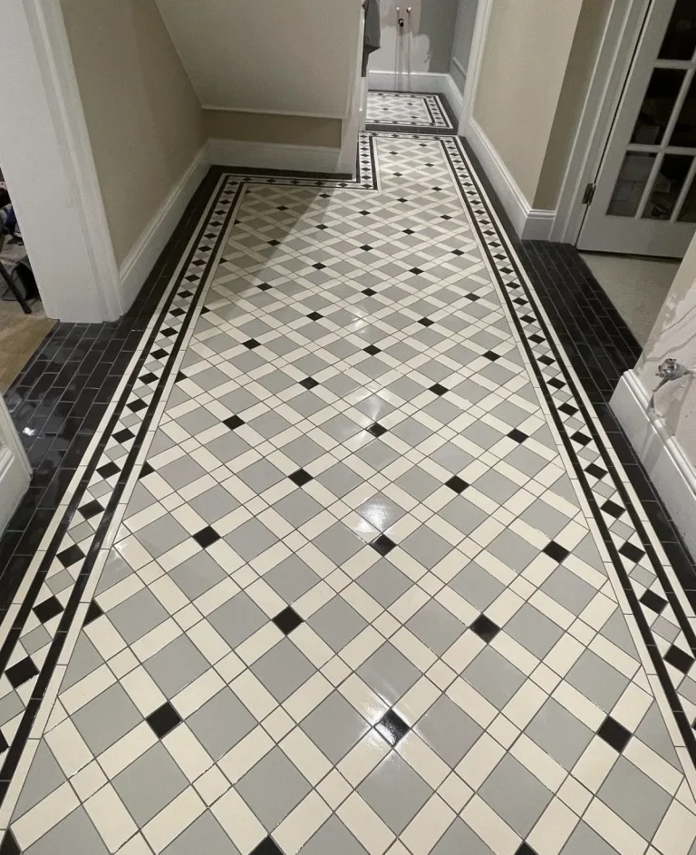 Restored Victorian geometric tiled hallway floor with black and grey border